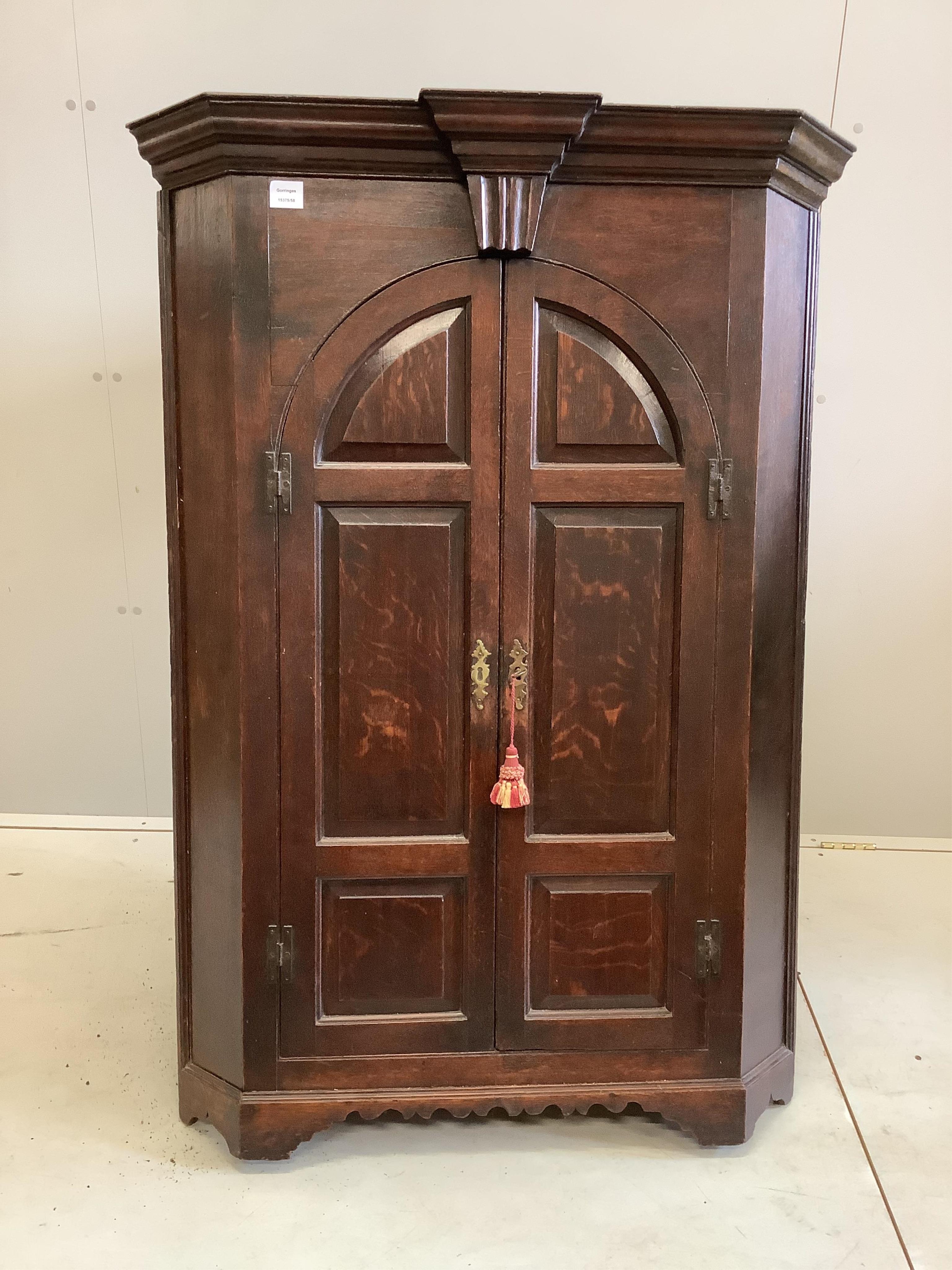 A George III oak hanging corner cupboard, enclosed by a pair of arched, fielded panelled doors, width 93cm, depth 59cm, height 134cm. Condition - fair